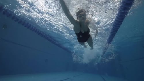 Sports Woman Floating Crawl Stroke in Blue Water Swimming Pool Underwater View.