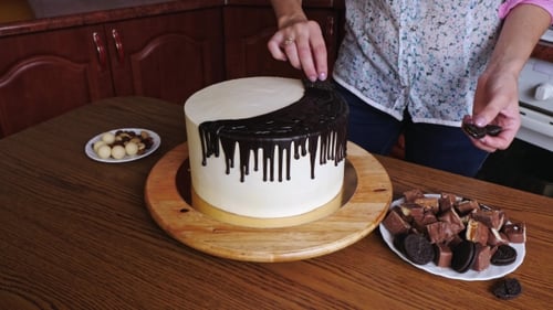 of Woman Hands Decoration a Cake with Chocolate and Pretzels, Nuts