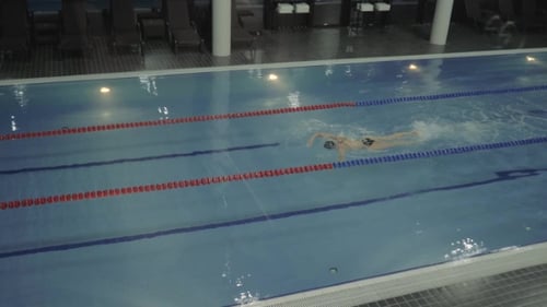 Female Professional Swimmer Floating Crawl Stroke in Water Luxury Swimming Pool
