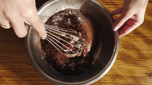 Cooking Cake. Woman Hands Mixing Flour and Cocoa Powder in Bowl. Top View.