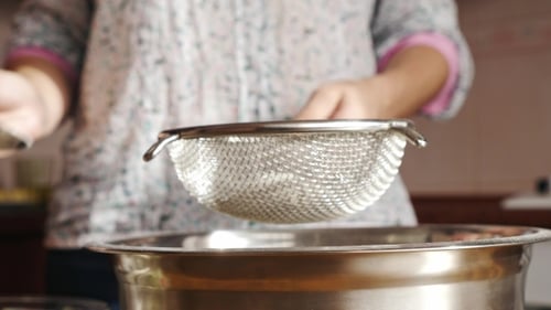 A Woman Hands Sifting Flour Into Bowl on Table