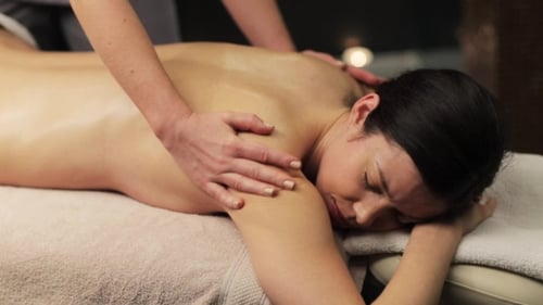 Liegende Frau und Rückenmassage im Spa 24