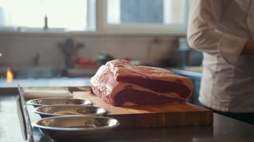 Chef Preparing Large Cut of Meat in Kitchen