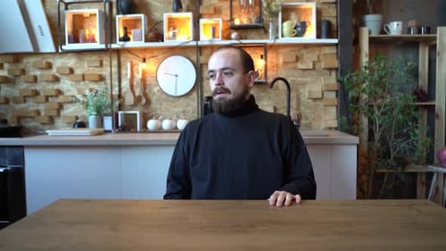 Stressed Man Sitting at Table in Kitchen