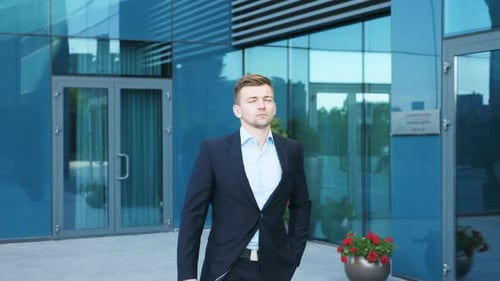 Young Businessman with a Briefcase Walking in City Street Near Modern Office Building. Confident Guy