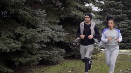 Man and Woman Jogging Through Park