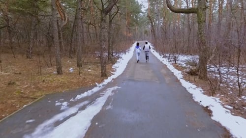 Young Man and Woman Runs in Winter Forest in the Morning