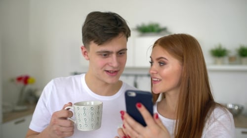 Couple Smiling Looking at Smartphone in Home