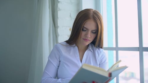 Woman Reading Book by Window in White Room
