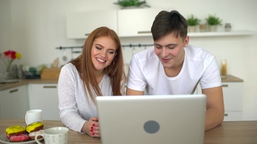 Smiling Couple Using Laptop Together in Bright Kitchen