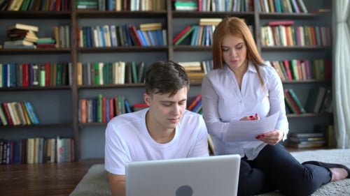 Male and Female Students Learning and Using Laptop in the Library. Two Students Brainstorm