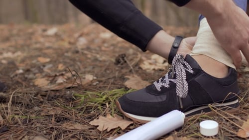 Applying Bandage to Ankle After Forest Hike