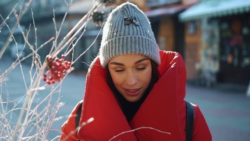 Beautiful Woman in Red Winter Jacket Walks Along the Street Covered with Snow in a Beautiful Old