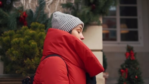 Beautiful Woman in Red Winter Jacket Walks Along the Street Covered with Snow in a Beautiful Old