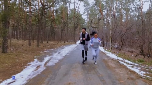 Young Man and Woman Runs Together in the Winter Forest