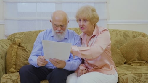 Senior Couple Reading Paperwork Together Indoors