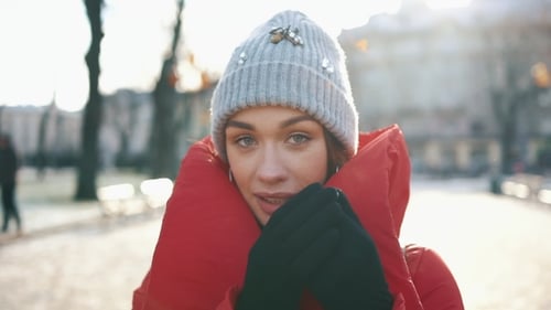 Portrait of a Stunning Girl in Grey Hat and Red Coat Smiling While She Stands on the Street Before