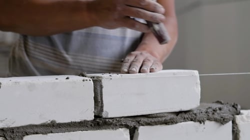 Builder Is Doing Brickwork, Hitting Over Brick By Trowel for Leveling and Taking Off an Excess