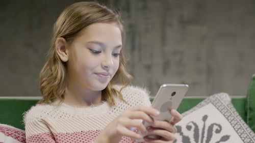Child Using Mobile Device on Sofa Indoors
