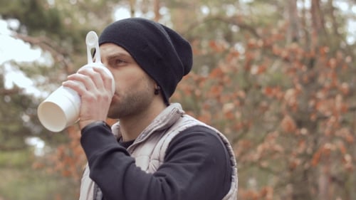 Young Man Drinks Water During Morning Running in the Forest