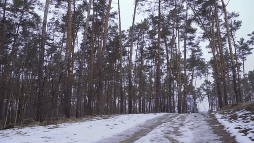 Young Sportswoman Looks on Her Wrist Watch and Continue Running in the Forest