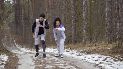 Couple Stretching Before Running in Snowy Forest