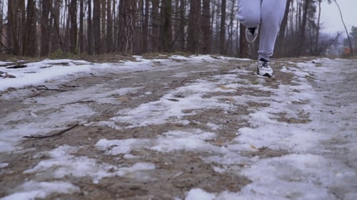 Woman in Snickers Runs Along Snow Road in