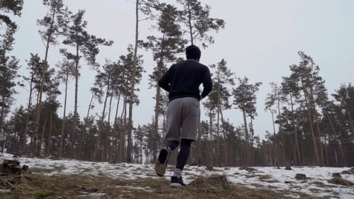 Man Runs in Snowy Forest on Winter Day