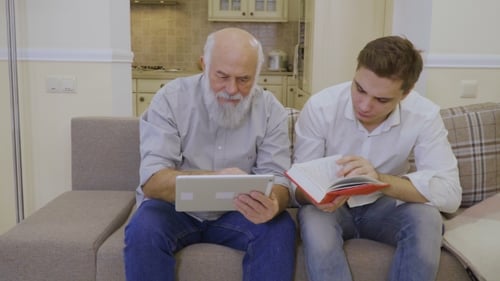 Senior Man and Young Adult Reading and Using Tablet