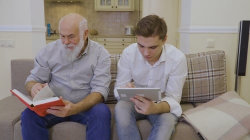 Senior Man and Young Man Using Tablet and Book