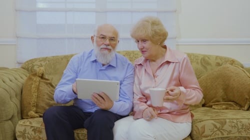 Senior Couple Using Tablet Together on Couch Indoors