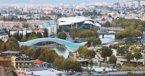 Tbilisi, Georgia. Aerial View, Cityscape View Of Kura Mtkvari River Under Pedestrian Bridge Of Peace