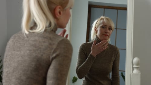 Woman Examining Face in Mirror