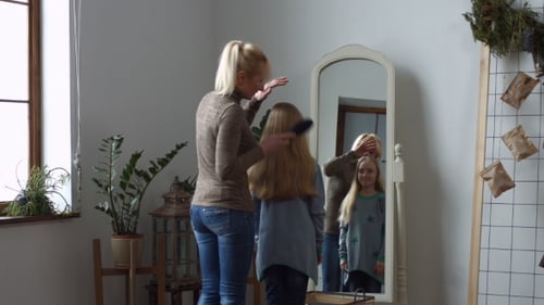 Woman Brushing Child's Long Blonde Hair at Home