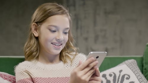 Girl Using Smartphone Smiling on Couch at Home