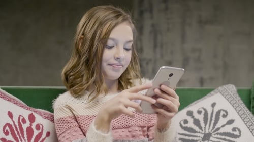 Smiling Child Typing on a Phone on Couch
