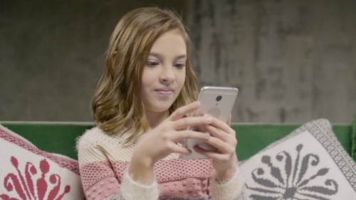 Girl Using Smartphone Sitting on Sofa Indoors