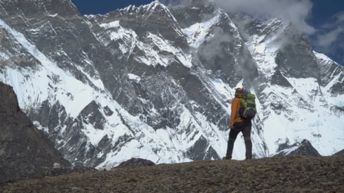 Man with Backpack Climb the Mountain Slope in the Himalayas