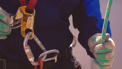 Hands Securing Climbing Rope Through Safety Harness