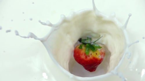 Fresa cayendo en crema lechosa en