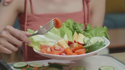 Close Up Of Woman's Hands Holding A Dish And Using A Fork Poking Carrots