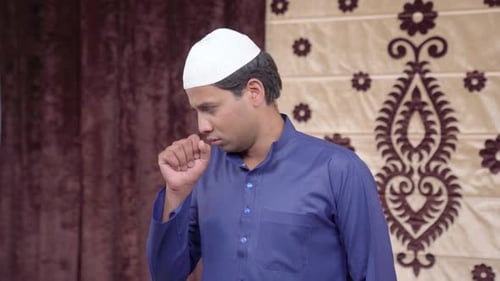 Man Coughing into Hand Indoors, Wearing White Knit Cap