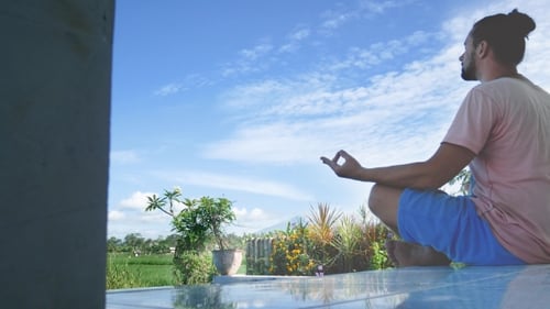 Man Sitting in Yoga Lotus Pose at Green Grass in the Meadow and Meditates