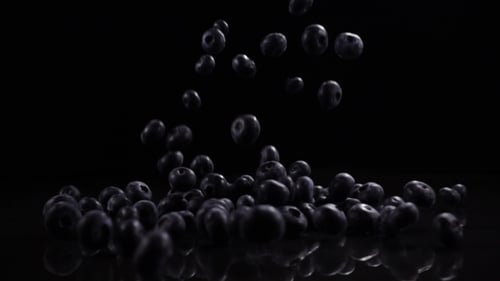 Blueberries Fall on a Black Solid Surface