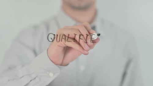 Hand Writes the Word Qualified on Glass