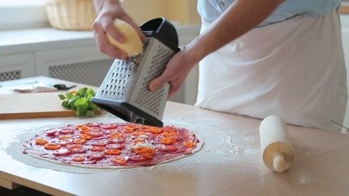 Man Prepares Pizza and Rubs Cheese