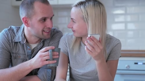 Couple Laughing at Phone in Bright Kitchen