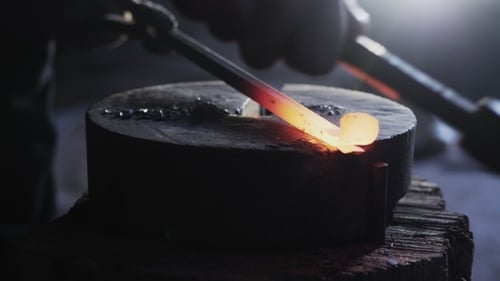 Blacksmith Shaping Hot Metal on Anvil with Hammer