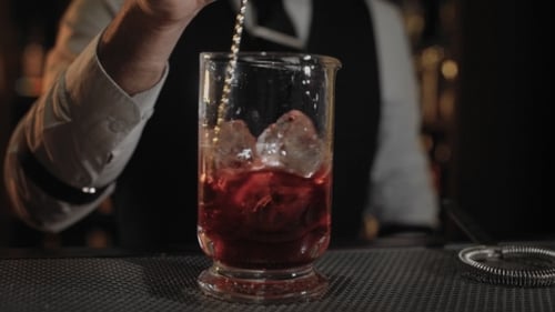 Adult Stirring a Red Cocktail with Ice