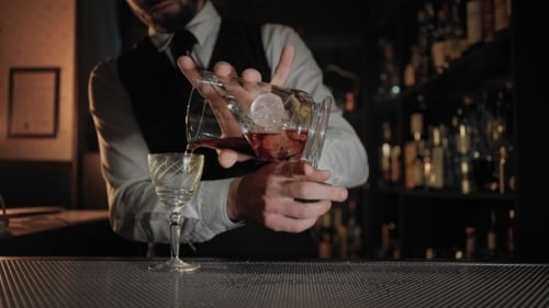 Professional Barman at Dark Lit Bar Prepares Drink